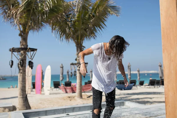 Jeune homme versé de l'eau sur la plage . — Photo