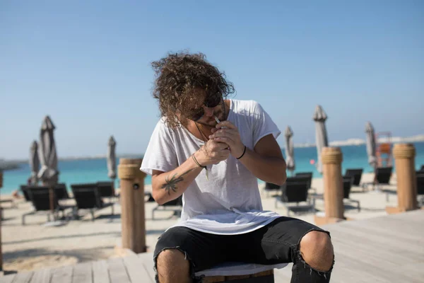 Homme élégant assis près de la plage et fumeur . — Photo