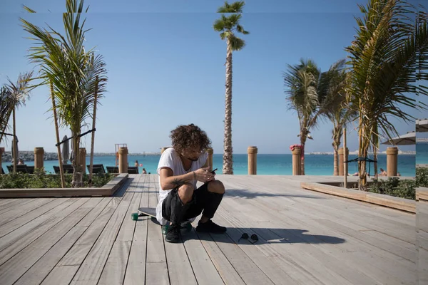 Homme élégant assis près de la plage et utilisant un smartphone . — Photo