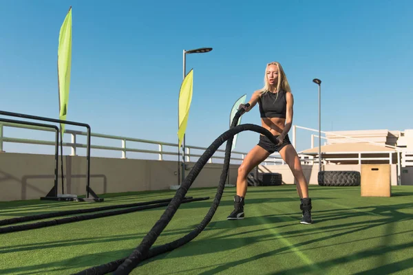 运动妇女在交叉训练健身房做战斗绳索练习. — 图库照片