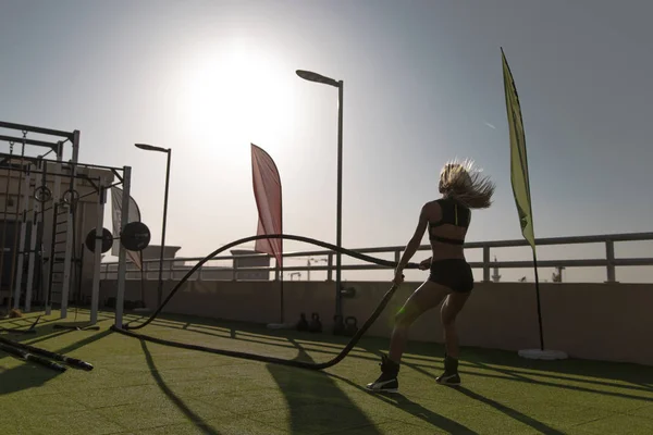 Sports woman doing battle ropes exercises in a cross training gym.