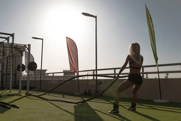 Sports woman doing battle ropes exercises in a cross training gym.