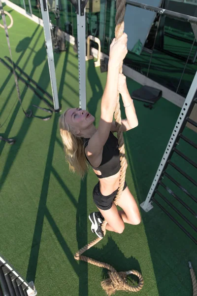 Muskulös kvinna gör rep klättring i crossfit gym. — Stockfoto