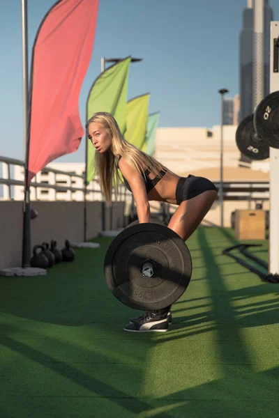 年轻的适合妇女重杠铃做 deadlift 的背部锻炼. — 图库照片