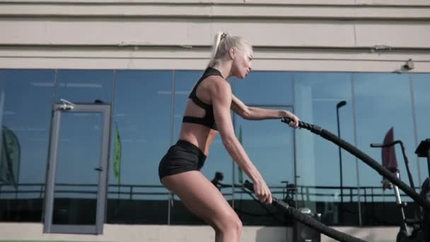 Mulher de esportes fazendo exercícios de cordas de batalha em um ginásio de treinamento cruzado . — Vídeo de Stock