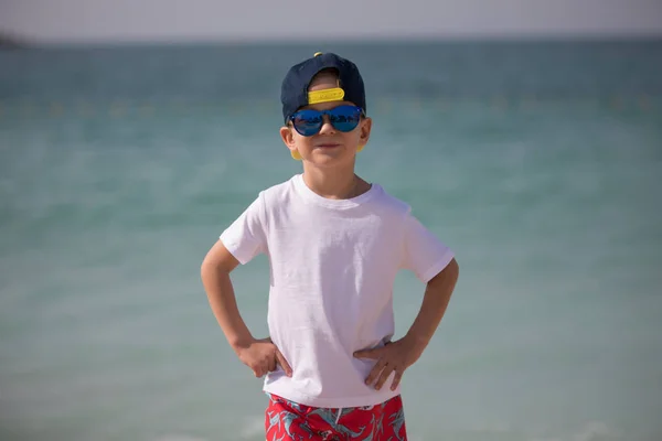 Mały chłopiec w okulary stoi na tle morza. — Zdjęcie stockowe