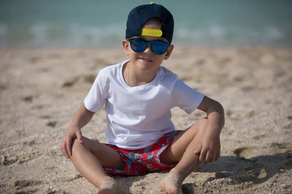 Kleine jongen zit op het zand. — Stockfoto