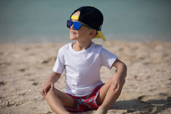 O menino está sentado na areia. . — Fotografia de Stock