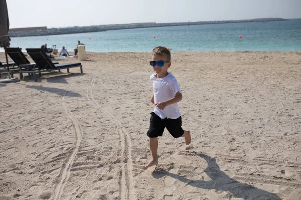 Beau petit garçon courant le long de la plage . — Photo