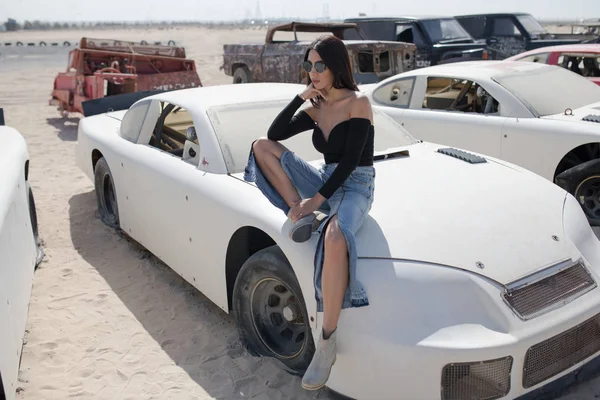 Mulher atraente senta-se no capô de um carro velho . — Fotografia de Stock