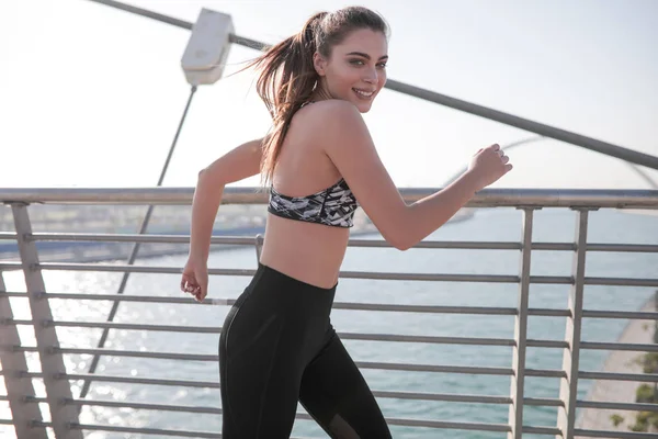 Donna attiva corridore jogging attraverso il ponte sul fiume, all'aperto corsa, sport e stile di vita sano concetto . — Foto Stock