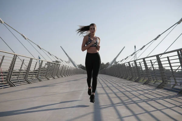 Active woman runner jogging across bridge, outdoors running, sport and healthy lifestyle concept.