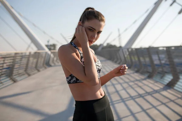 Junge sportliche Frau mit Kopfhörern, die draußen Musik hört. — Stockfoto