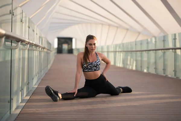 Femme sportive faisant des exercices d'étirement sur un pont . — Photo