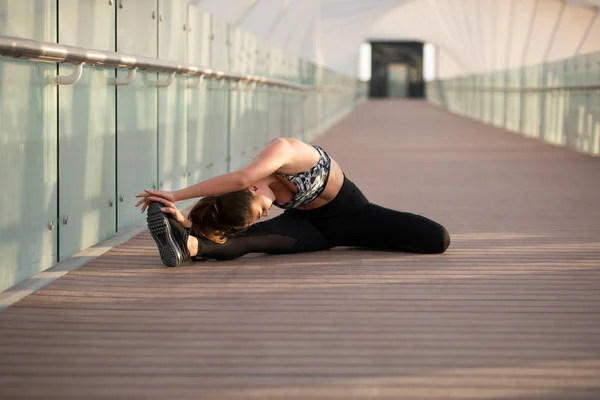 Mulher de esportes fazendo exercícios de alongamento em uma ponte . — Fotografia de Stock