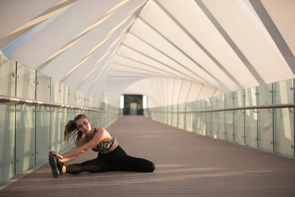 Bir köprüde spor kadının yapması germe egzersizleri. — Stok fotoğraf