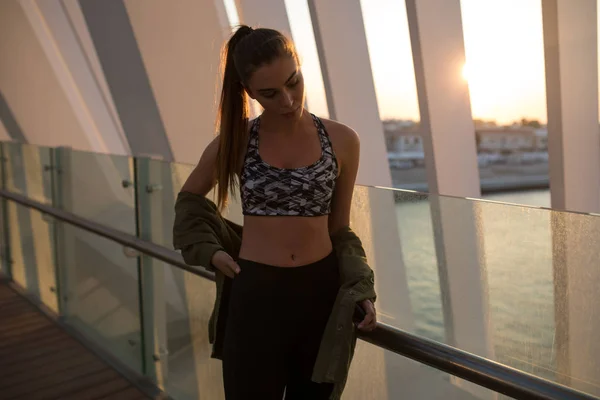 Corredor feminino atraente em sportswear descansando após a corrida da noite, esporte fora ao pôr do sol incrível . — Fotografia de Stock