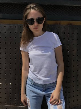 Çekici kız beyaz tişört, metal bir arka plan üzerinde duruyor.