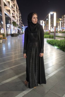 Gece şehirde bir hijab giyen Müslüman kadın yürüyor.