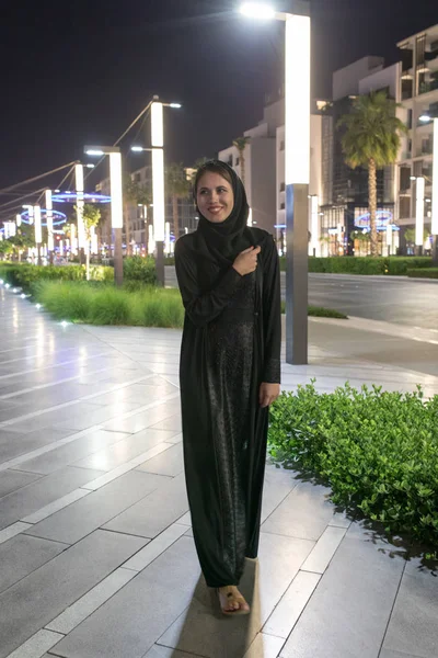 Muslim woman wearing in a hijab walks in the night city. — Stock Photo, Image