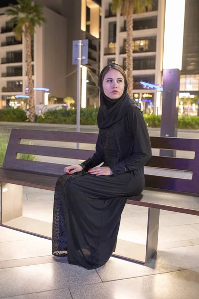 Muslim woman wearing in a hijab sits on a bench in the city. — Stock Photo, Image