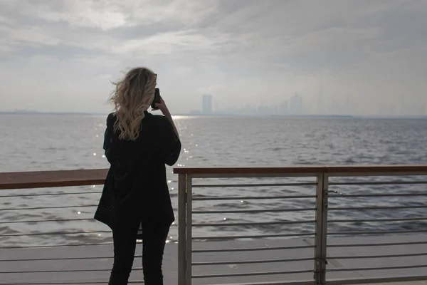 从海洋侧面拍摄城市照片的妇女的后视图. — 图库照片