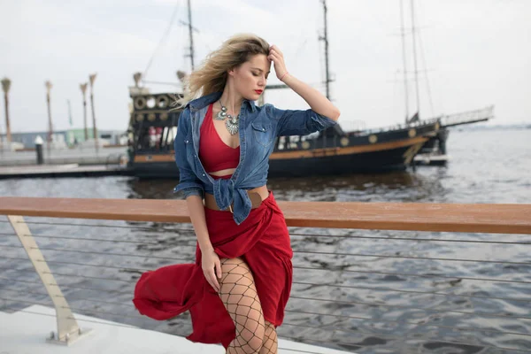 Beautiful woman in a red dress on a ship background.