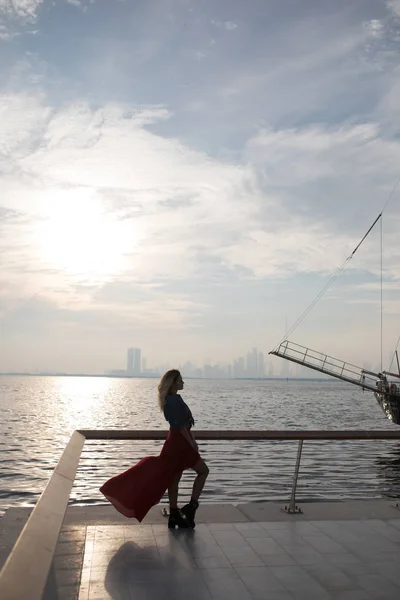 Vacker kvinna i röd klänning på bakgrunden av havet. — Stockfoto