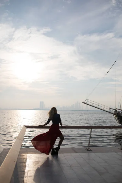 Vacker kvinna i röd klänning på bakgrunden av havet. — Stockfoto