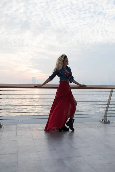 바다의 배경에 빨간 드레스에 아름 다운 여자. — 스톡 사진