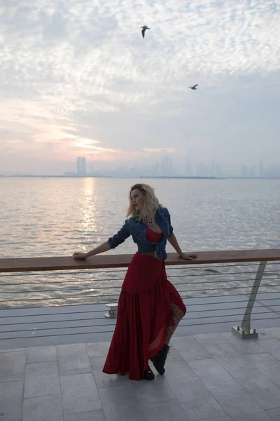 바다의 배경에 빨간 드레스에 아름 다운 여자. — 스톡 사진