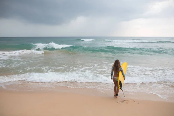 Surfer Girl innehar en styrelse och går in i havet. — Stockfoto