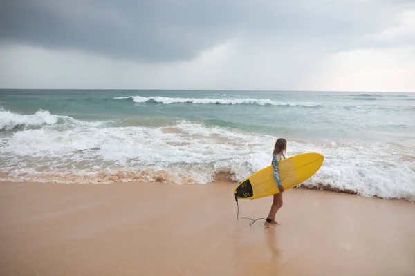 Vacker kvinna surfare står på ocean bakgrunden med surfbräda i händer. — Stockfoto