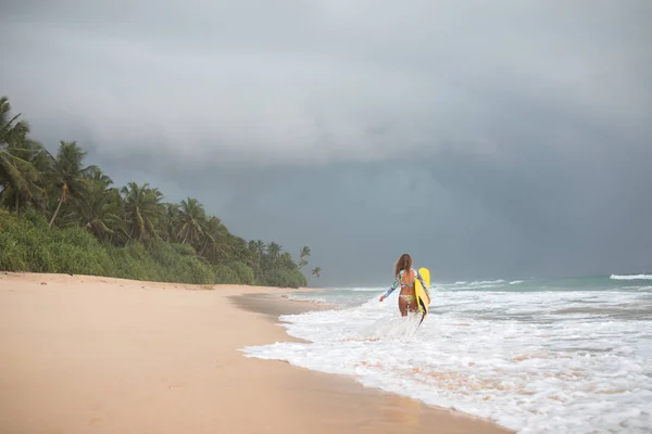 Surfer Girl innehar en styrelse och går in i havet. — Stockfoto