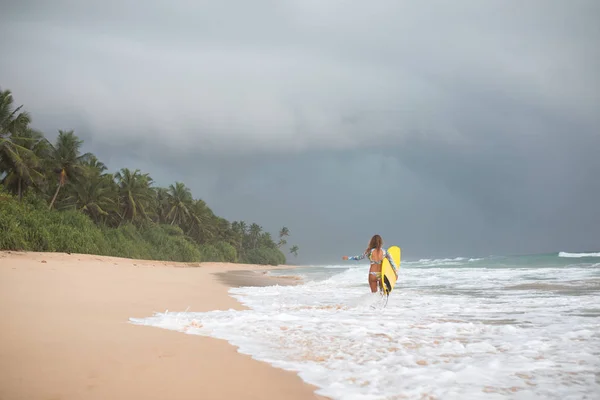 Surfer Girl innehar en styrelse och går in i havet. — Stockfoto