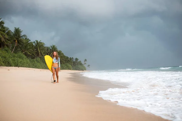 Kvinnliga surfare promenader längs havet med en styrelse i händer. — Stockfoto