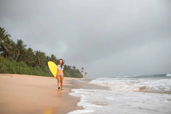 Kvinnliga surfare promenader längs havet med en styrelse i händer. — Stockfoto