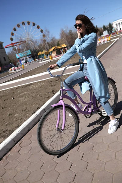 Stylish young woman riding a bicycle. — Stock Photo, Image