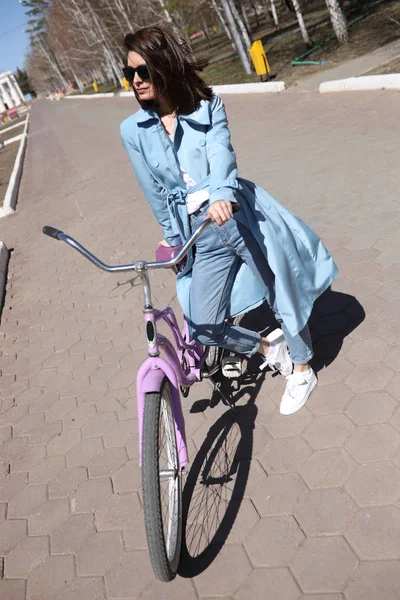 Stylish young woman walking along the street with a bicycle. — Stock Photo, Image