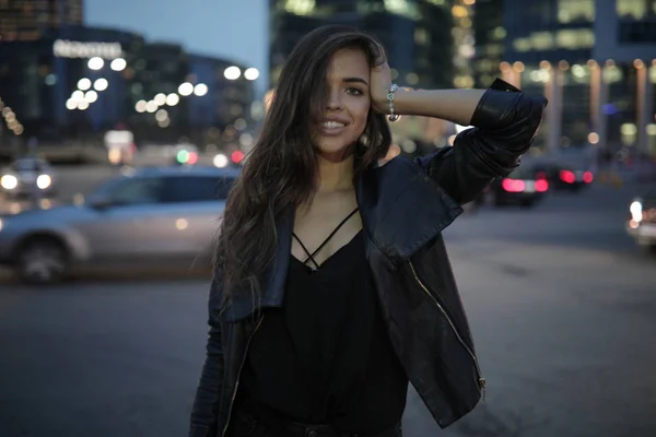 Hermosa mujer en el fondo de una ciudad nocturna y coches que pasan . —  Fotos de Stock