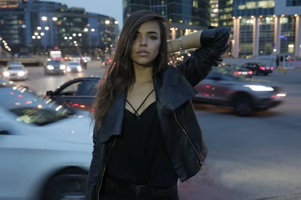 Vacker kvinna på en bakgrund av en natt staden och passerar bilar. — Stockfoto