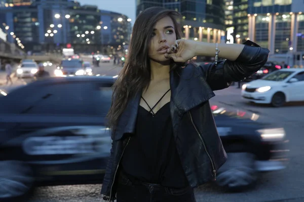 Mooie vrouw op een achtergrond van een nacht stad en passerende auto 's. — Stockfoto