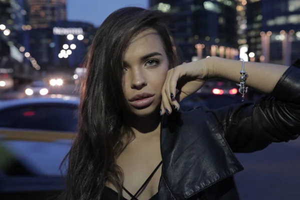 Hermosa mujer en el fondo de una ciudad nocturna y coches que pasan . —  Fotos de Stock