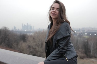 Şehir Manzaralı köprüde oturan şık genç kadın.