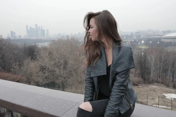 Elegante giovane donna seduta sul ponte con vista sulla città . — Foto Stock