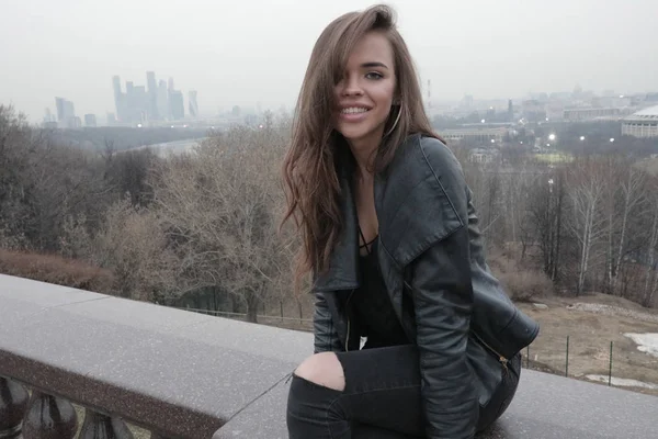 Elegante giovane donna seduta sul ponte con vista sulla città . — Foto Stock