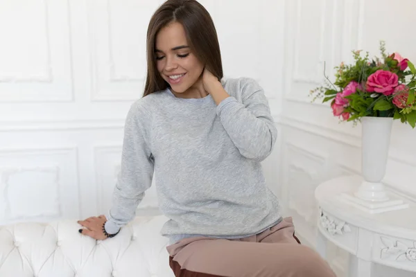 Hermosa mujer en sudadera gris sentada en el sofá. Mock-up . — Foto de Stock