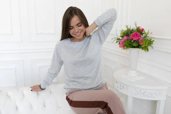 Hermosa mujer en sudadera gris sentada en el sofá. Mock-up . — Foto de Stock