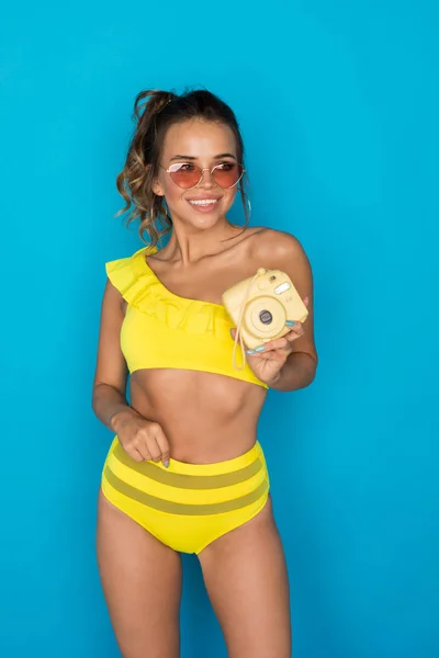 Szexi fiatal nő fényes sárga fürdőruhában, polaroid van a kezében.. — Stock Fotó