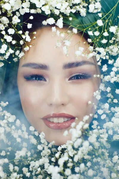 Portrait de belle fille en fumée avec de petites fleurs blanches autour de son visage. Femme et fleurs. Printemps . — Photo